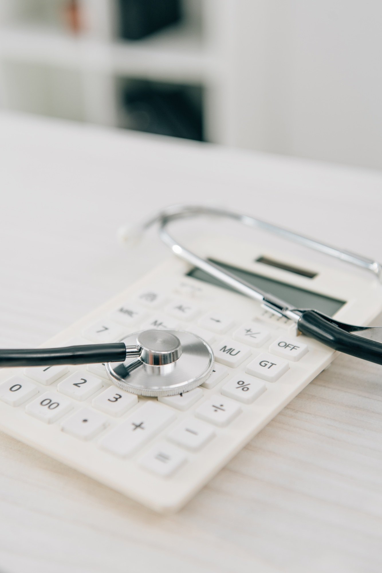 stethoscope lying on white calculator, health insurance concept