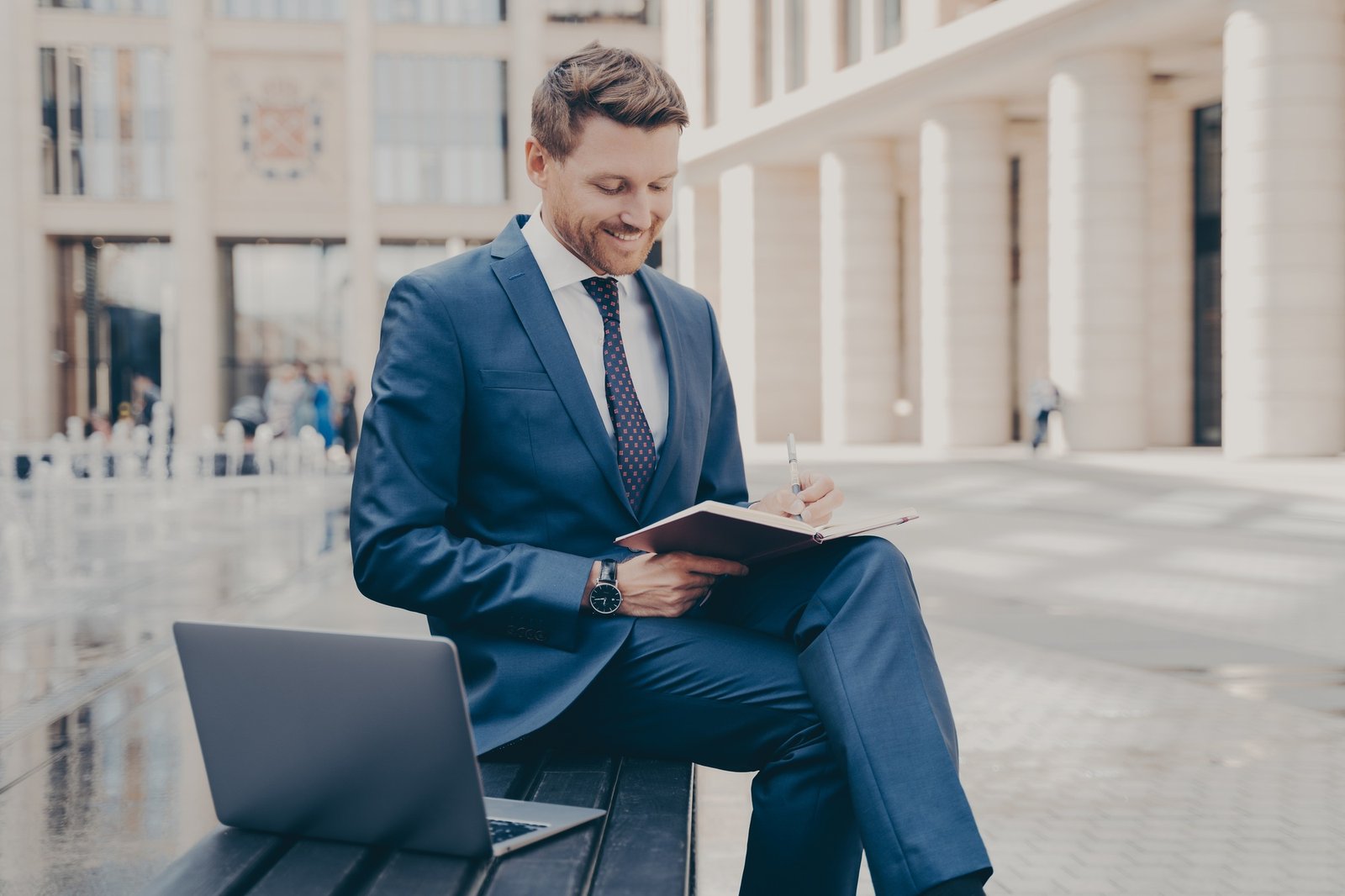 Successful business owner writing down information in notebook while working outdoors on weekend